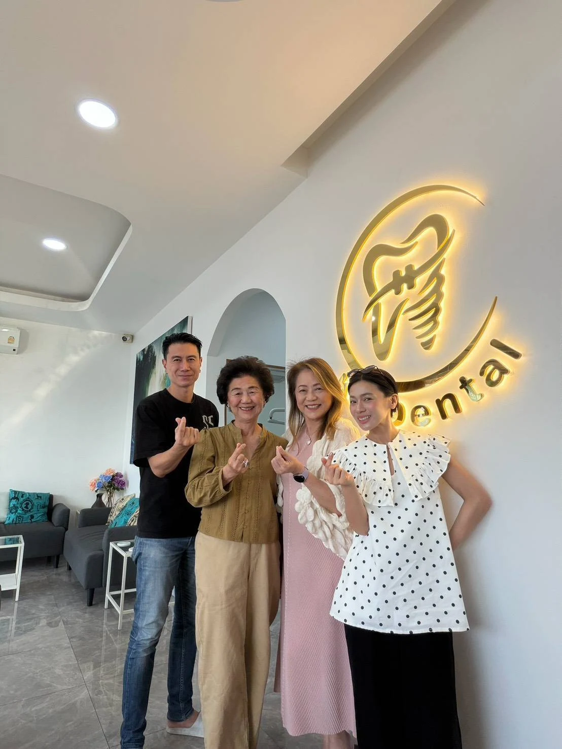 A group sharing a moment at the KP Dental Clinic logo wall