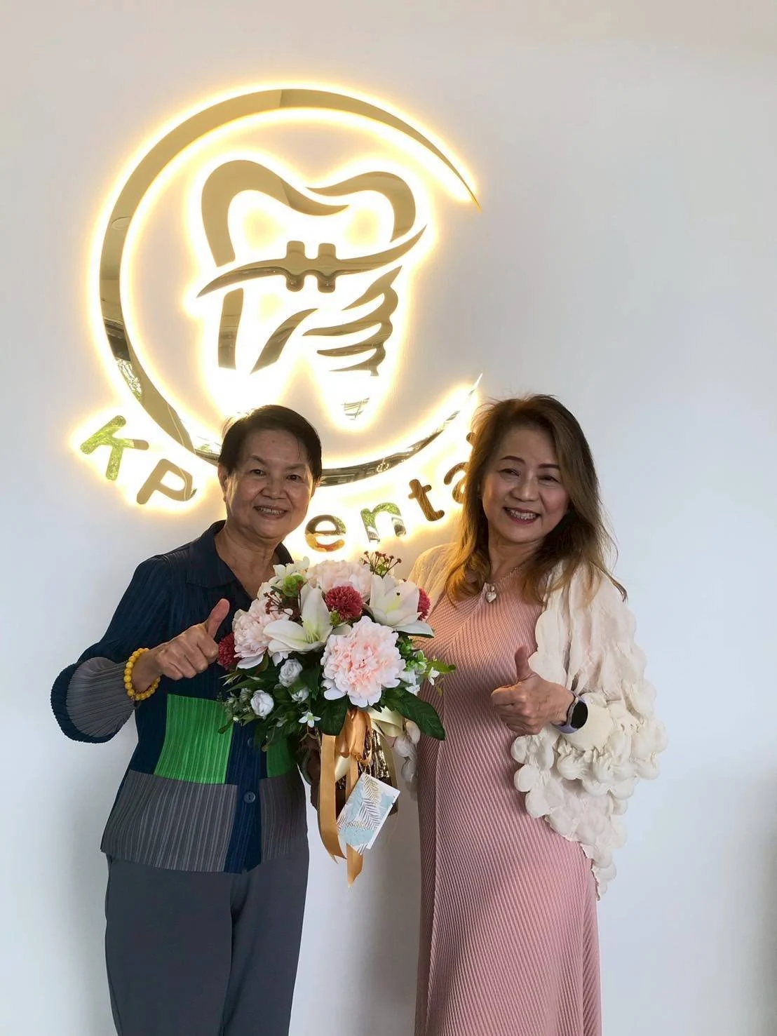 A warm moment beside the KP Dental Clinic logo